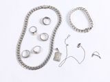 a lot of silver jewelry on a white surface