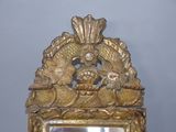 a mirror that has a gold frame with a picture on it