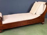 une chaise longue en bois garnie de coussins, dans une pièce