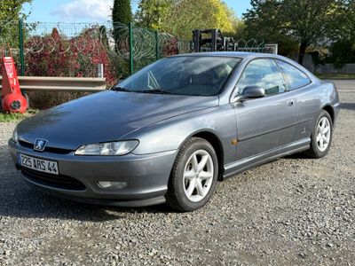 a silver car that is parked in the gravel
