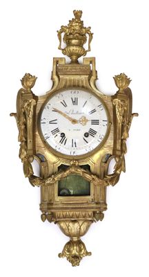 a gold clock on the wall with roman numerals on it