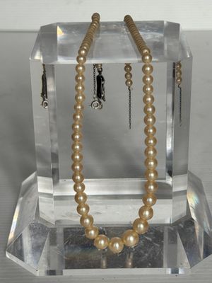 un collier de perles exposé sur un socle en verre transparent