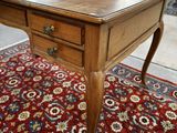 an image of a wooden desk with drawers on top of a red rug