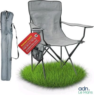 une chaise de jardin avec un parasol et un sac posés sur l'herbe