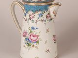 a white and blue coffee pot with flowers on it