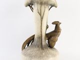 a white vase with a bird on it and a mushroom on the side