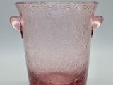 vase en verre rose muni de deux anses, posé sur un fond blanc