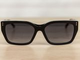 black sunglasses on a wooden table with a white wall in the background