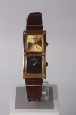 a gold watch with a black face on a stand