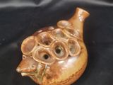 un vase marron orné d'un visage, posé sur un tissu noir