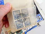 une personne tenant un morceau de papier sur lequel figurent des timbres