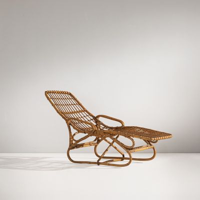 une chaise longue en rotin avec une assise en osier posée sur un socle blanc