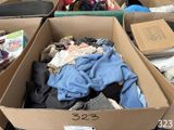 de nombreux cartons remplis de vêtements et des vêtements éparpillés par terre