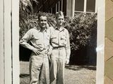 two men in uniform standing next to each other in front of a house