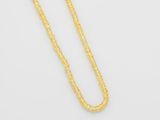 un collier en or dont la chaîne est posée sur un fond blanc