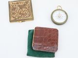 a wallet, a pocket watch, and a pocket watch on a table