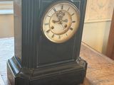 a black clock sitting on top of a wooden table