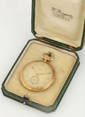 a gold pocket watch in a case on a white surface