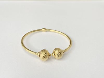 a close up of a gold bracelet with two balls on it