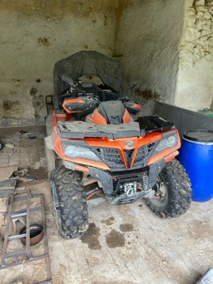 un quad orange garé dans un garage, à côté d'un seau bleu