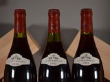 three bottles of red wine sitting on top of a wooden crate