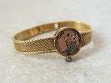 une image montrant un gros plan d'une bague en or sur laquelle figure une horloge