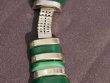 necklace with green glass and silver accents on a gray background