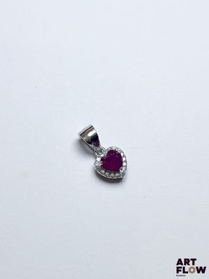 un gros plan d'un pendentif en forme de cœur posé sur une surface blanche