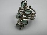 a close up of a silver ring with green stones on it