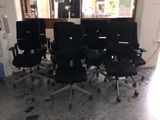 six chaises de bureau noires dans une pièce avec une fenêtre en arrière-plan