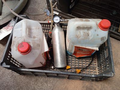 deux bidons en plastique posés dans un panier à côté d'un bidon d'essence