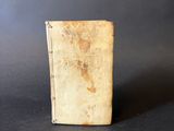 an old book sitting on top of a table on a black surface