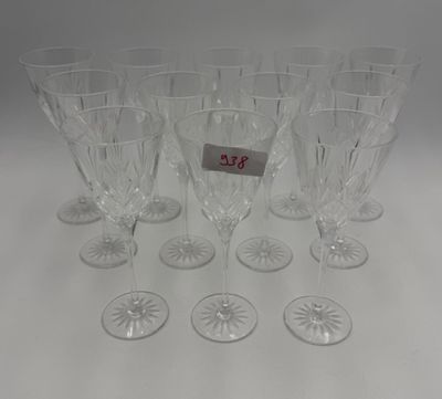 six clear wine glasses are lined up on a white surface