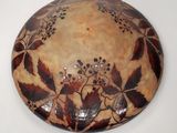 une assiette marron et noire décorée de feuilles et de baies