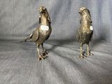 une paire d'oiseaux en métal de couleur argentée sur fond gris