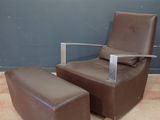 un fauteuil et un pouf dans une pièce, avec un mur en arrière-plan