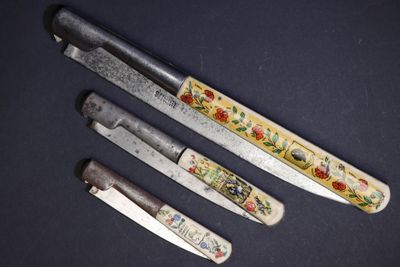 trois couteaux sont assis l'un à côté de l'autre sur une table