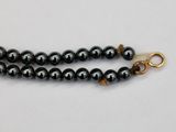 a close up of a black beaded necklace with a gold clasp