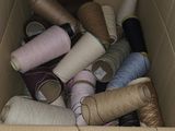 many spools of thread in a box on the floor