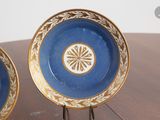 two blue plates with gold designs on them sitting on a table