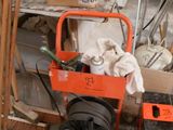 un petit chariot orange contenant des outils dans une pièce