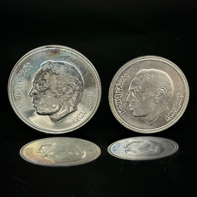 deux pièces d'argent posées l'une à côté de l'autre sur une surface noire