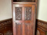 a tall wooden cabinet in the corner of a room with a green chair