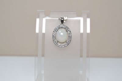 a glass display case with a white stone pendant on it