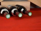 several bottles of wine sit in a wooden crate on a red cloth