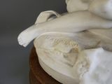 une statue représentant une femme allongée sur un socle en bois