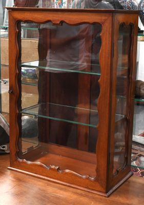 une vitrine en bois avec des étagères en verre, dans une pièce
