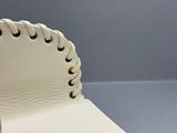 un gros plan sur un chapeau en cuir blanc orné d'un bord tressé