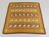 yellow and brown scarf with horses on it on a white surface