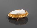 a gold plated broochle with a white stone in the center